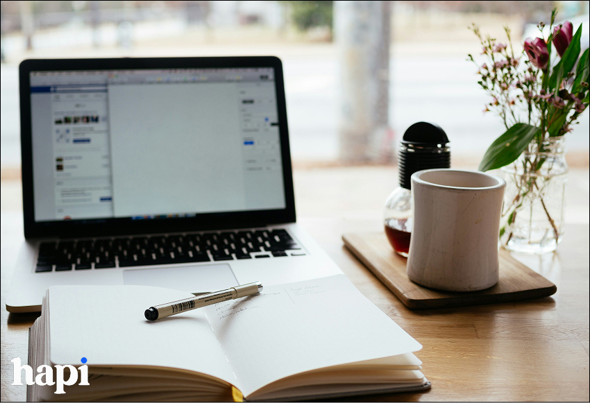 A work table with an open notebook and laptop on it
