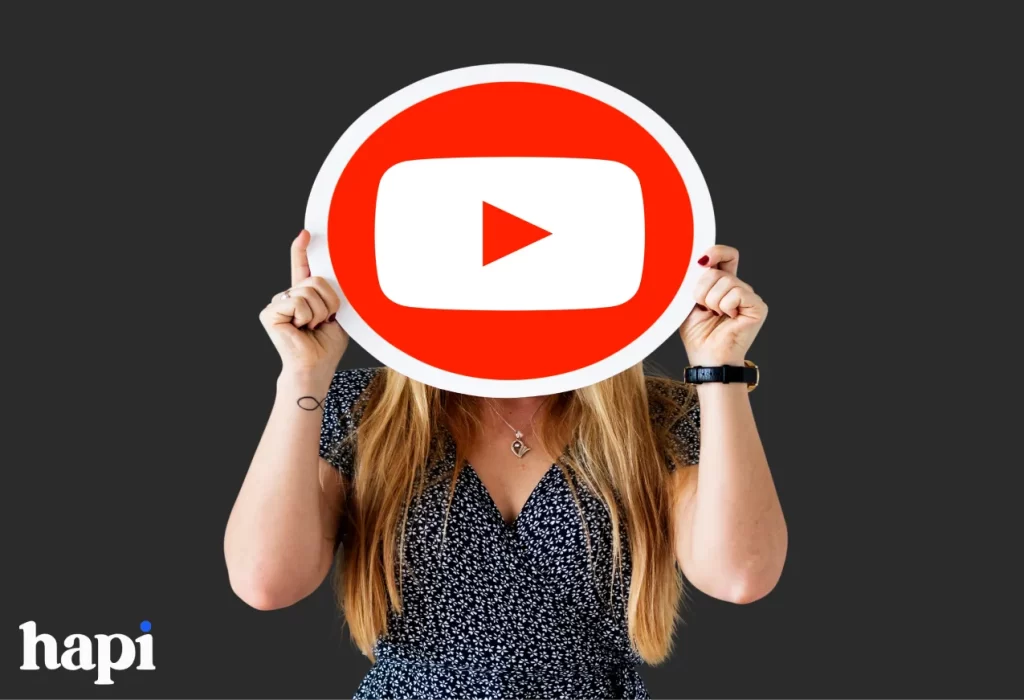 A blond woman holding the youtube sign in front of her face