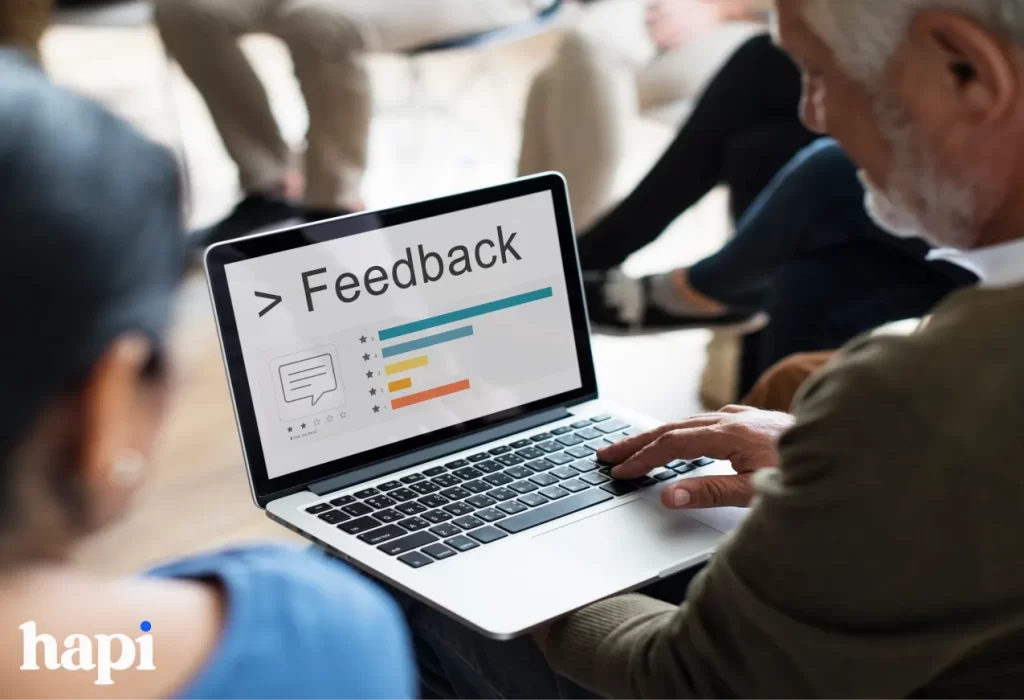 A group of people looking at a laptop with the word feedback on it