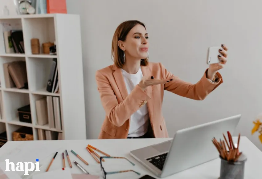 a woman sending a kiss to a phone she is holding in her hand