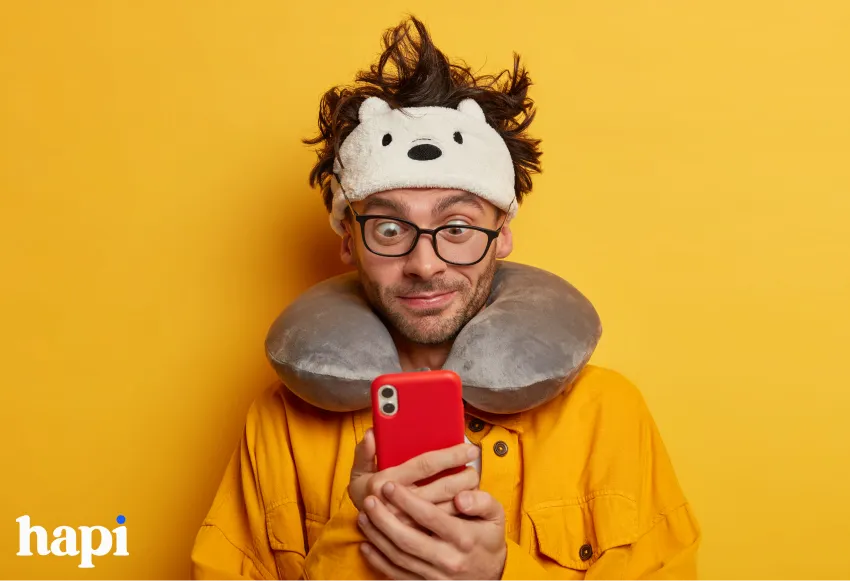 A man with a cute headband smiling amusedly at his phone
